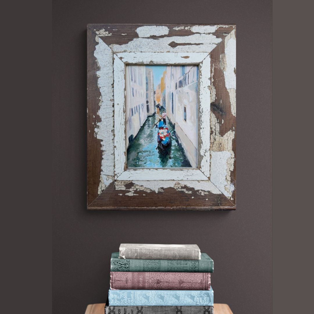 A small oil painting of Gondolas in Venice framed in an upcycled wooden frame.